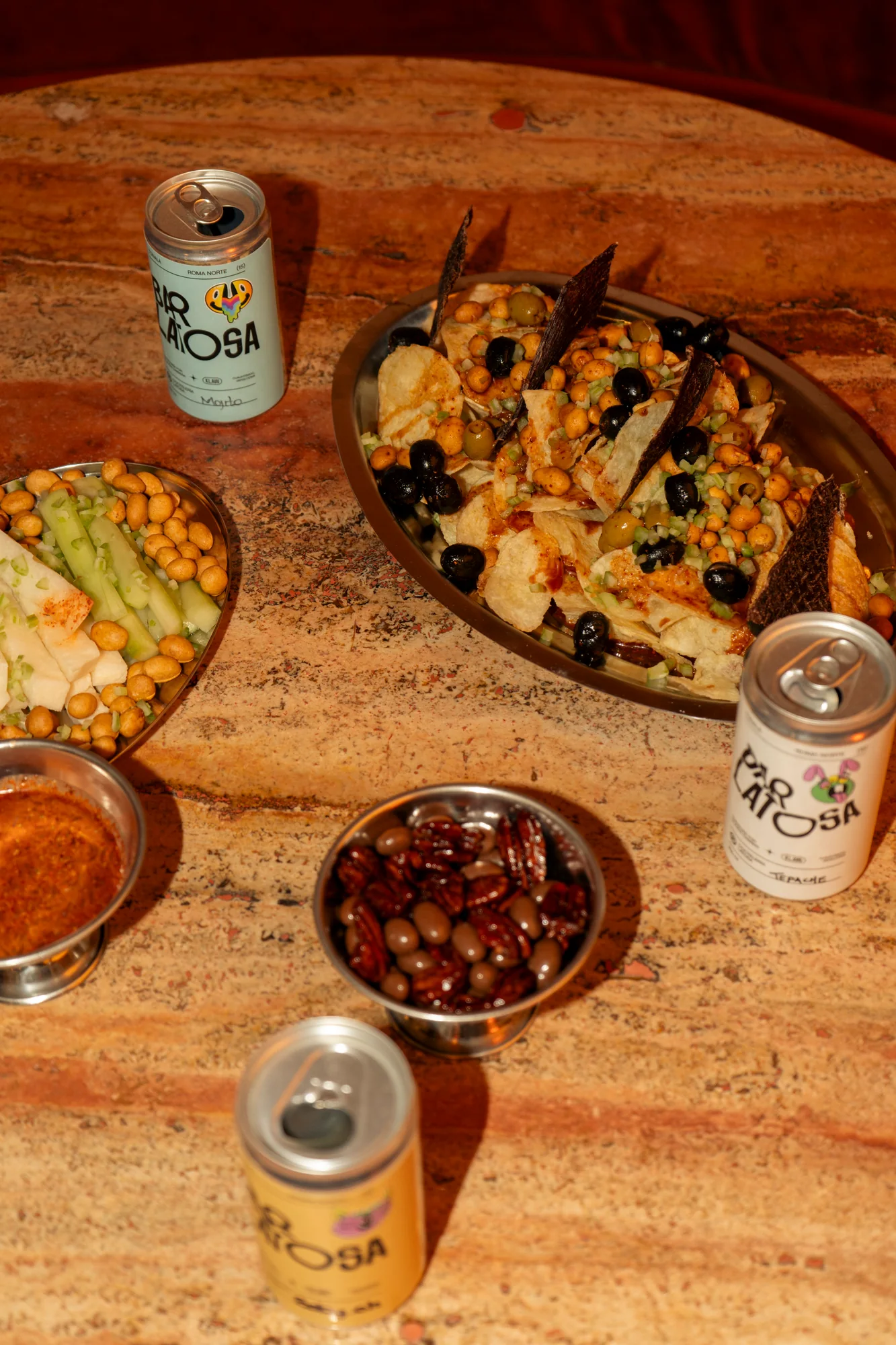 Mesa con latas de Bar Latosa y botanas para compartir.